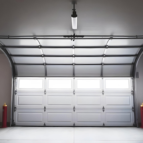 Overhead garage door partially open in a warehouse, showcasing robust design and functionality. Overhead garage door manufacturer in India for secure and efficient operations.